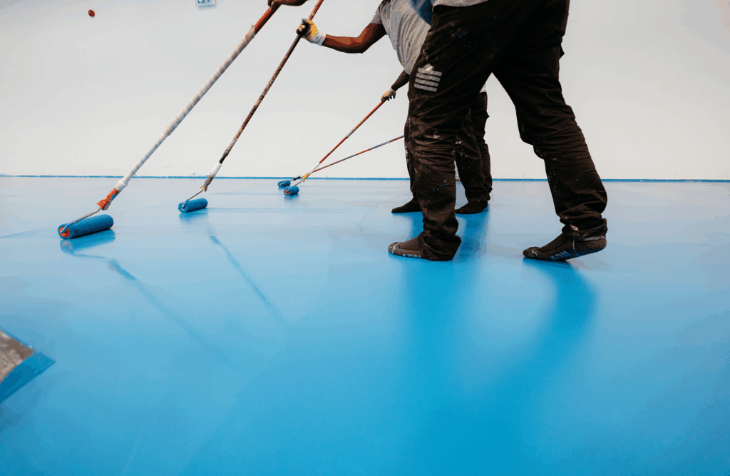 Pinturas Flores, Impermeaibilizaciones de alta calidad en Alcalà de Xivert. Cuatro trabajadores impermeabilizando un suelo de color azul.