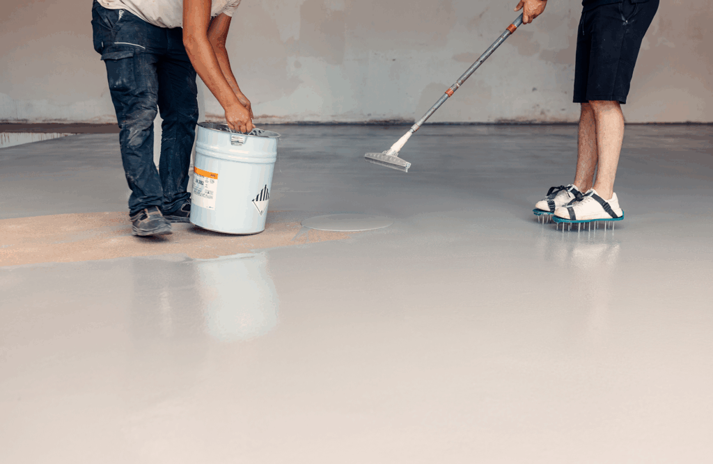 Pinturas Flores, Impermeaibilizaciones de alta calidad en Benicarló. Un par de trabajadores impermeabilizando el suelo con resina gris.