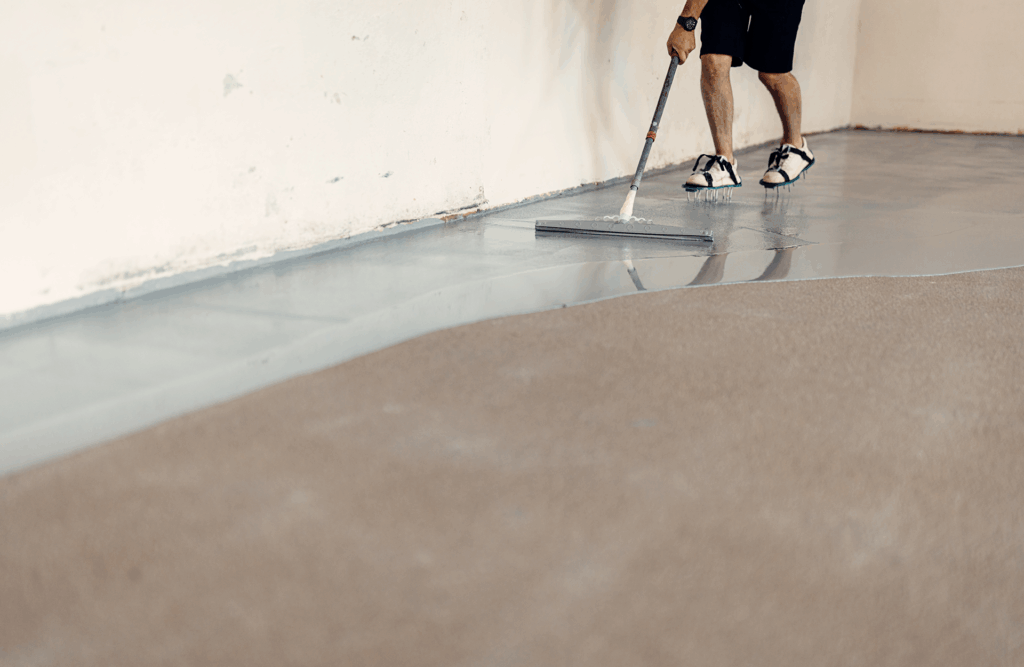 Pinturas Flores, Impermeaibilizaciones de alta calidad en Sant Jordi. Un trabajador impermeabilizando el suelo de una sala grande con resina gris.