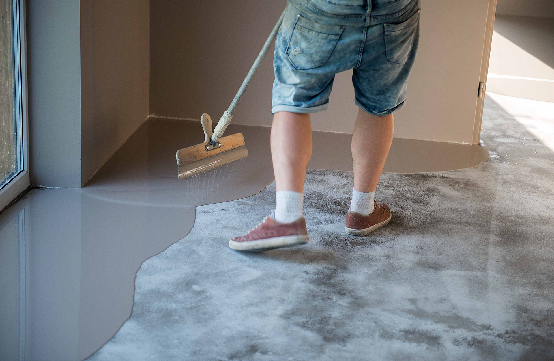 Pinturas Flores, Impermeaibilizaciones de alta calidad en Vinaròs. Un trabajador impermeabilizando el suelo de un salón con resina gris.