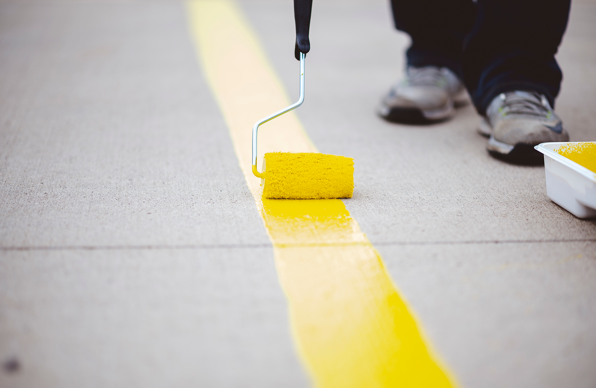 Pinturas Flores, pintores expertos de parkings y comunidades en Benicarló. Pintor repasando una linea amarilla con amarillo.