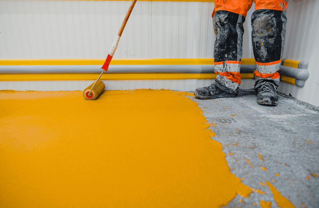 Pinturas Flores, pintores expertos de parkings y comunidades en Peñíscola. Persona acabando de aplicar una capa de amarillo en el suelo.
