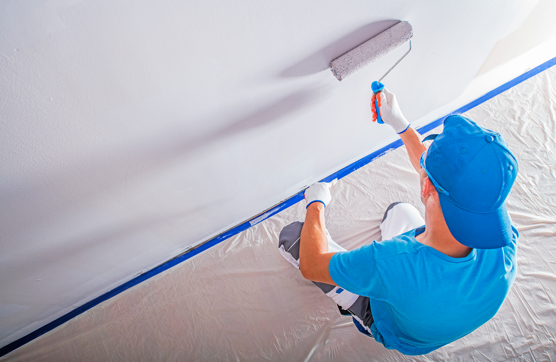 Pinturas Flores, pintores expertos de parkings y comunidades en Sant Jordi. Pintor de azul con un rodillo aplicando una segunda capa de blanco a la pared.