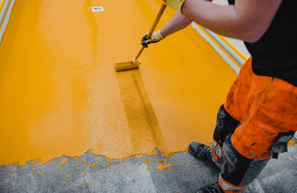 Pinturas Flores, pintores expertos de parkings y comunidades en Vinaròs. Pintor ligeramente tocando la pintura amarilla mientras pinta el suelo.