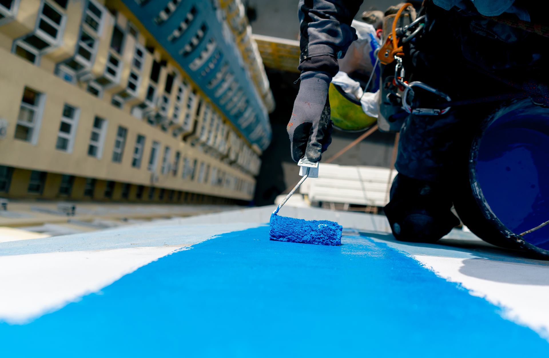 Pinturas Flores, Revestidores de fachadas cualificados en Càlig. Pintor pintando una fachada de azul con su mano derecha.