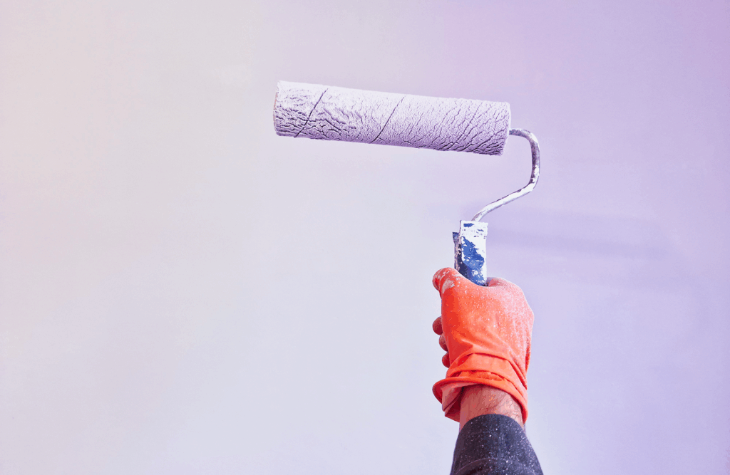 Pinturas Flores, servicios de pintura profesionales en Cálig. Rodillo de color violeta pastel enfrente de una pared violeta pastel.