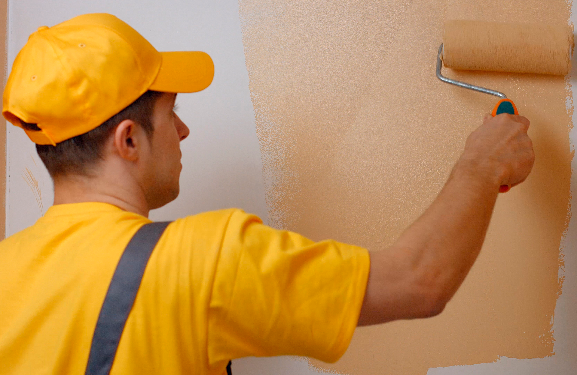 Pinturas Flores, servicios de pintura profesionales en Cervera del Maestre. Pintor aplicando una segunda capa de amarillo a la pared.