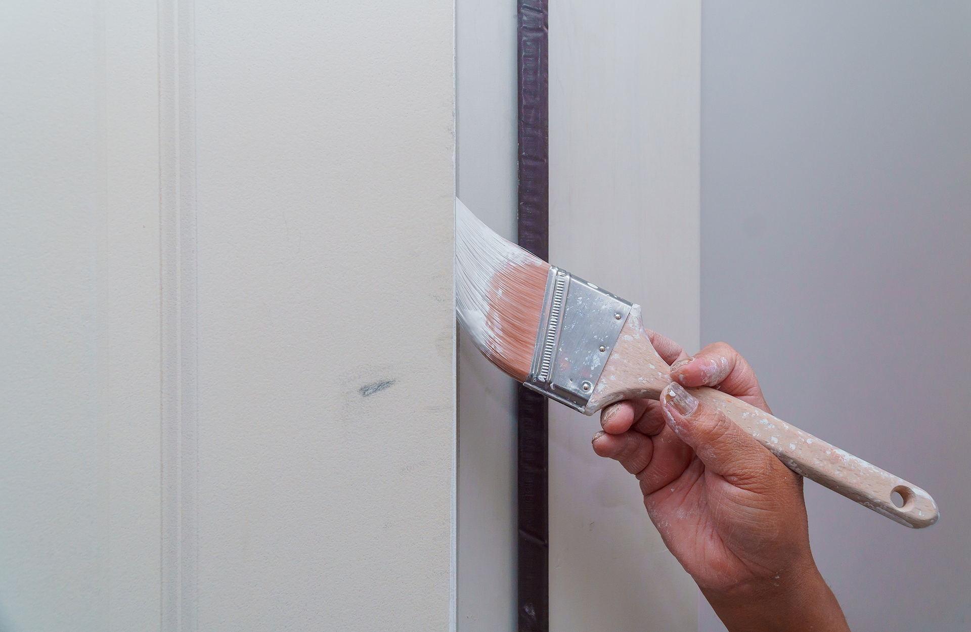 Pinturas Flores, servicios de pintura profesionales en Cervera del Maestre. Persona perfilando los bordes con una brocha con pintura blanca.