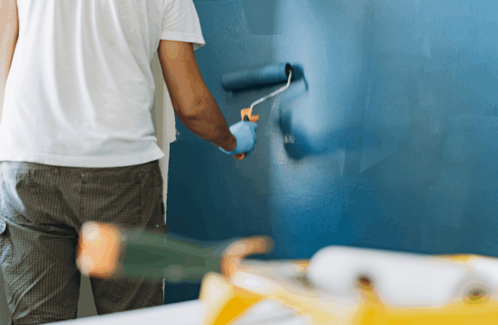 Pinturas Flores, servicios de pintura profesionales en Vinaròs. Persona aplicando una segunda capa de azul a la pared.