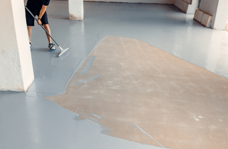 Pinturas Flores, Impermeaibilizaciones de alta calidad en La Jana. Un trabajador impermeabilizando el suelo de una sala muy grande con resina gris.