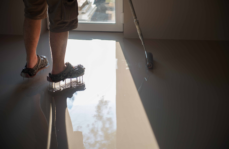 Pinturas Flores, Impermeaibilizaciones de alta calidad en Traiguera. Un trabajador junto a una ventana impermeabilizando el suelo con resina gris.
