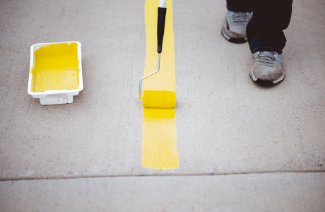 Pinturas Flores, pintores expertos de parkings y comunidades en Cervera del Maestre. Pintor perfilando una linea amarilla con amarillo.