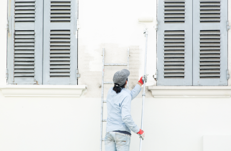 Pinturas Flores, Revestidores de fachadas cualificados en Alcalà de Xivert. Pintor pintando de blanco una pared entre 2 ventanas.