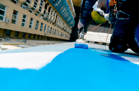 Pinturas Flores, Revestidores de fachadas cualificados en Alcalà de Xivert. Pintor pintando una fachada de azul con su mano derecha desde lejos.