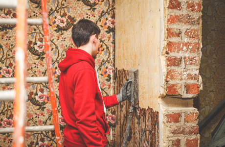 Pinturas Flores, instaladores de papel tintado experienciados en Benicarló. Hombre con sudadera roja retirando papel tintado.
