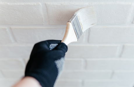 Pinturas Flores, servicios de pintura profesionales en La Jana. Persona pasando una brocha por una pared de ladrillos,