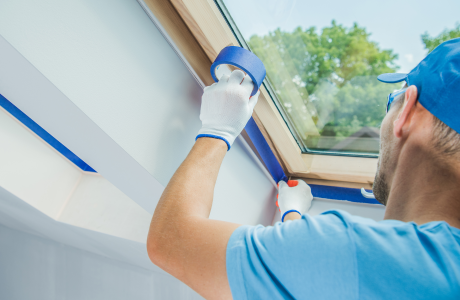 Pinturas Flores, servicios de pintura profesionales en Sant Jordi. Pintor sellando los bordes de una ventana con cinta aislante.